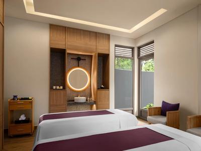 Modern hotel room with two beds, wood paneling, and natural light from windows.