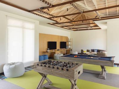 Modern lounge with foosball table, pool table, seating area, and large window.
