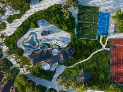 Aerial view of a recreational area with tennis courts and a pool surrounded by trees.