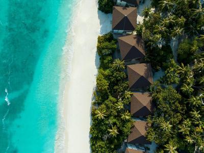Tropical resort with bungalows along a white sandy beach and clear turquoise water.