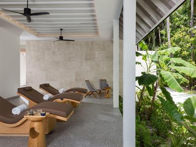 Relaxation area with lounge chairs and view of tropical plants and palm trees outside.