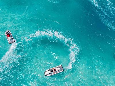Tři skútry na tyrkysové vodě s viditelnými vodními stopami