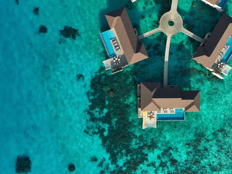 Three overwater bungalows with pools on turquoise ocean