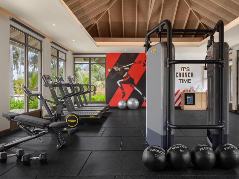 Modern gym with equipment and large windows in a hotel.