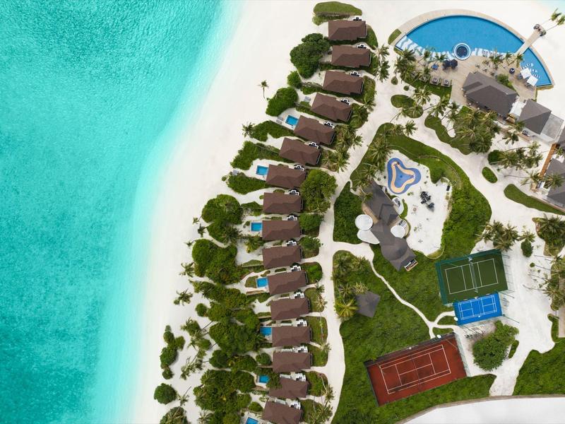 Aerial view of a resort with villas lined up along a turquoise beach.