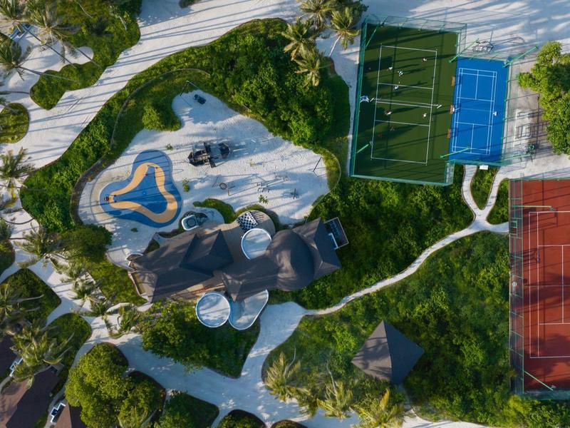 Aerial view of a recreational area with tennis courts and a pool surrounded by trees.