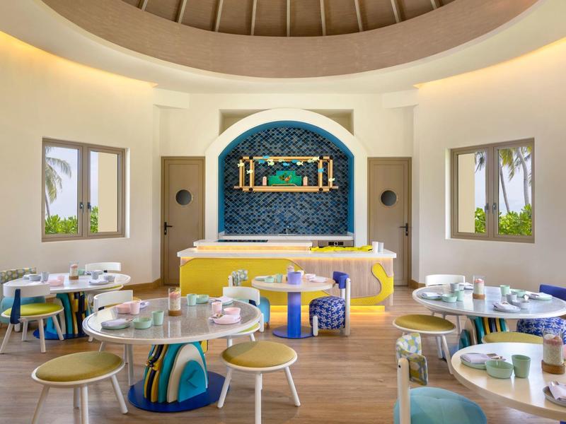 Bright, modern breakfast room with colorful chairs and buffet in the background.