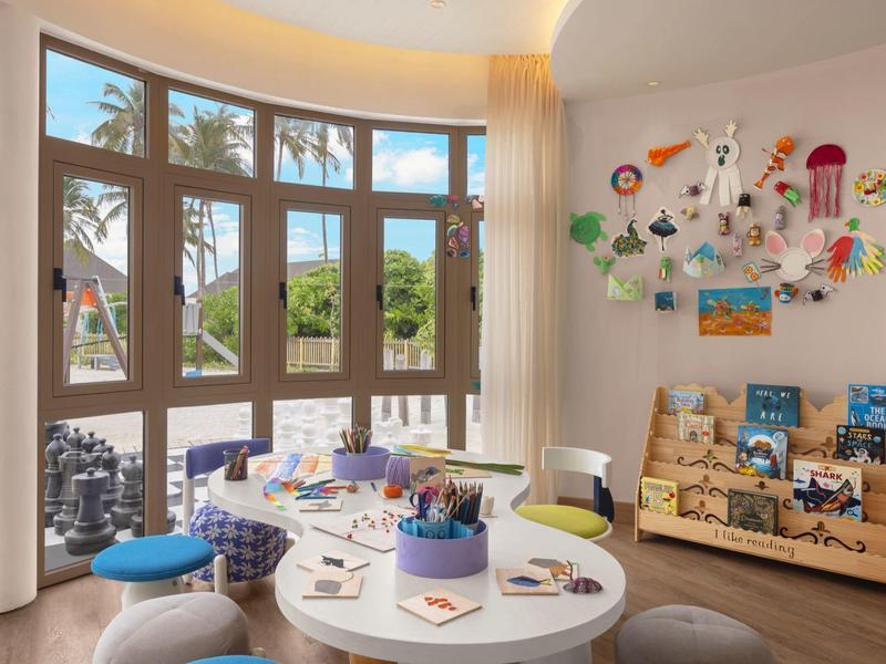 Bright play area with large window, colorful furniture, and wall decorations in a hotel.