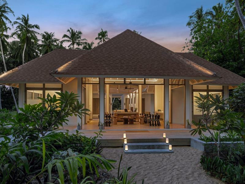 Bright bungalow hotel room with open terrace and tropical garden at sunset.