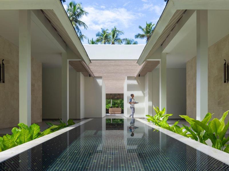 Modern hotel complex with a long, narrow water feature and tropical plants.