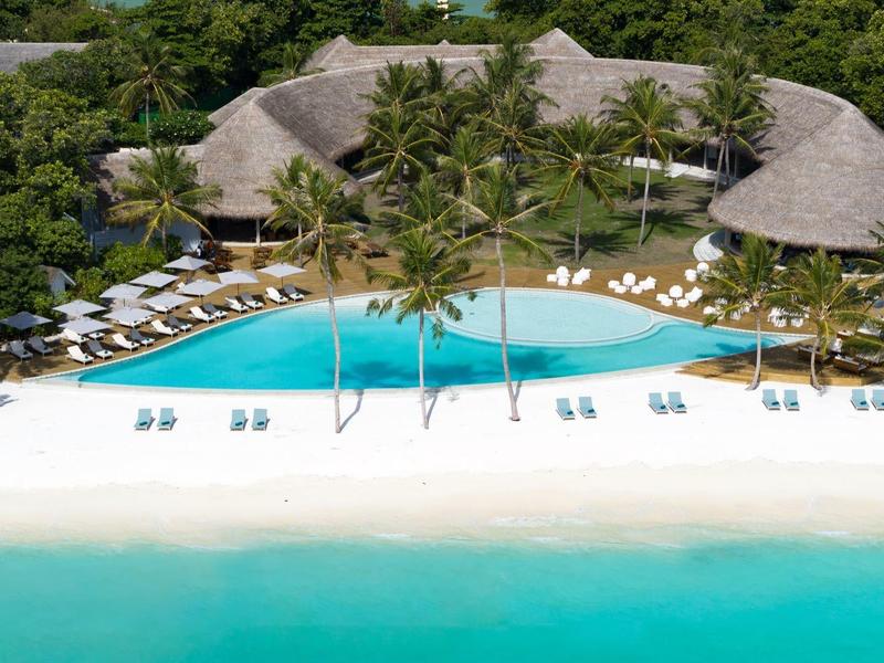 Luxusní plážová vila s bazénem, obklopená palmami u tyrkysového moře.