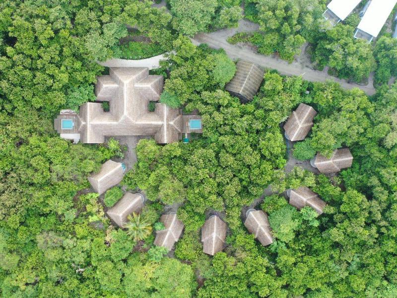 Letecký pohled na hotelový komplex s několika budovami obklopenými hustou zelení.