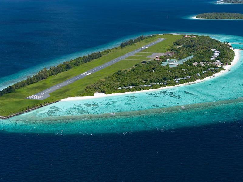 Letecký pohled na tropický ostrov s přistávací dráhou, plážemi a tyrkysovou vodou.