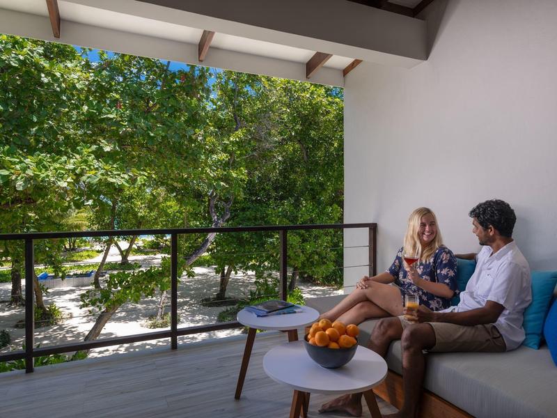 Balkon s pohovkou a stolem s výhledem na zelené stromy a park