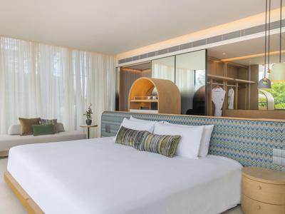 Lichte hotelkamer met groot bed, zithoek en modern design.