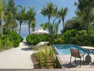 Modern buitenzwembad met terrasmeubilair en palmbomen bij tropisch resort