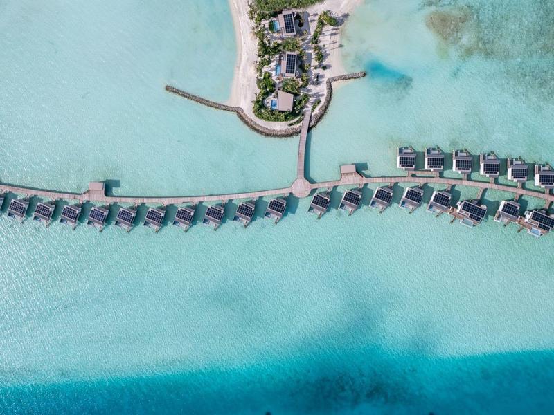 Luchtfoto van een tropisch resort met bungalows boven het turquoise water