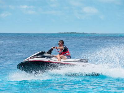 Person fährt mit einem Jetski über blaues Meer vor klarem Himmel