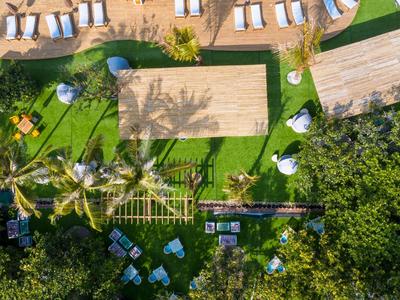 Vue aérienne d'une piscine d'hôtel avec chaises longues, parasols et jardin vert.
