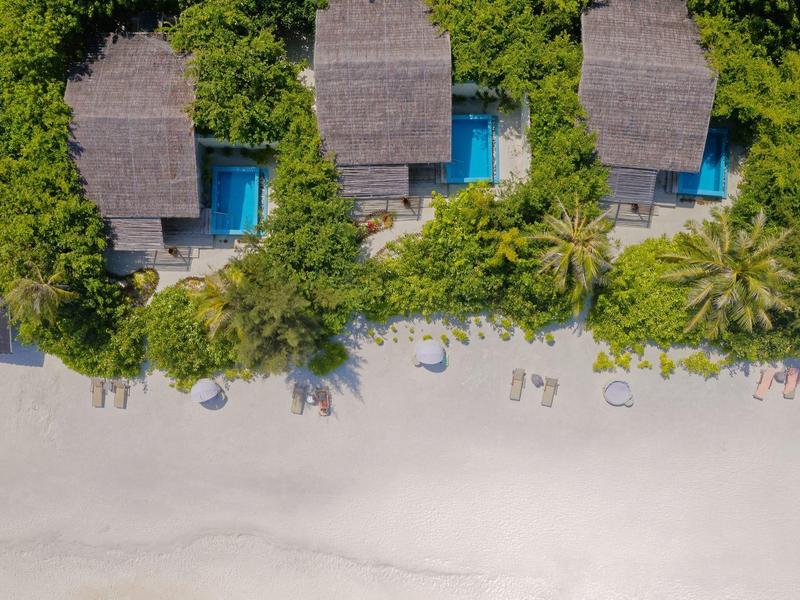 Trois villas de plage avec piscines et transats entourées de verdure luxuriante et de sable blanc.