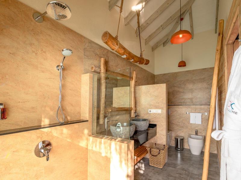 Salle de bain moderne avec douche, lavabo en pierre, détails en bois et éclairage lumineux.