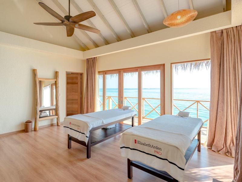 Salle de bien-être lumineuse avec deux tables de massage et vue sur l'océan