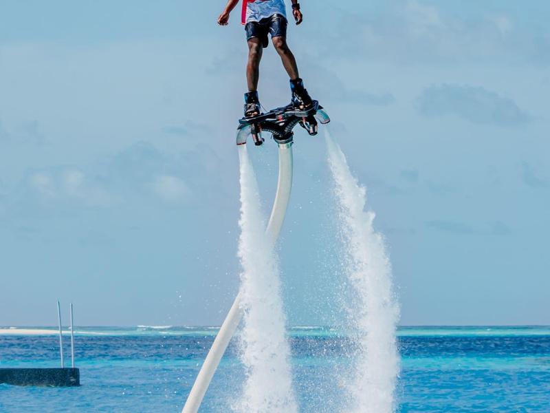 Personne volant avec un flyboard au-dessus de la mer bleue par une journée ensoleillée.