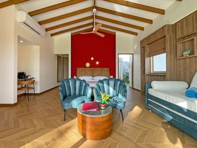 Chambre d'hôtel moderne avec coin salon, sol en bois et poutres apparentes au plafond.