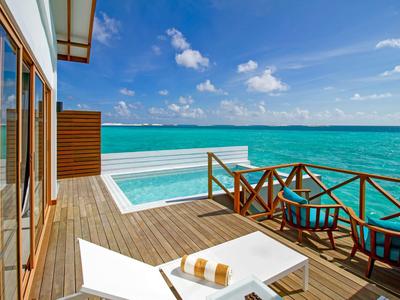 Terrasse sur pilotis avec chaises longues et piscine privée sous un ciel dégagé.