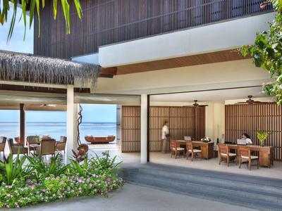 Area pranzo aperta con vista sul mare e giardino tropicale.