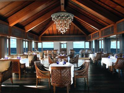 Ristorante elegante con tetto in legno, grandi finestre e aree salotto di design con vista sul mare.