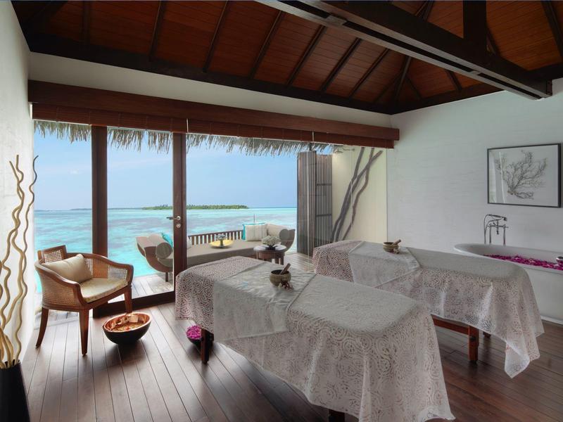 Sala benessere luminosa con lettini da massaggio e vista sul mare.