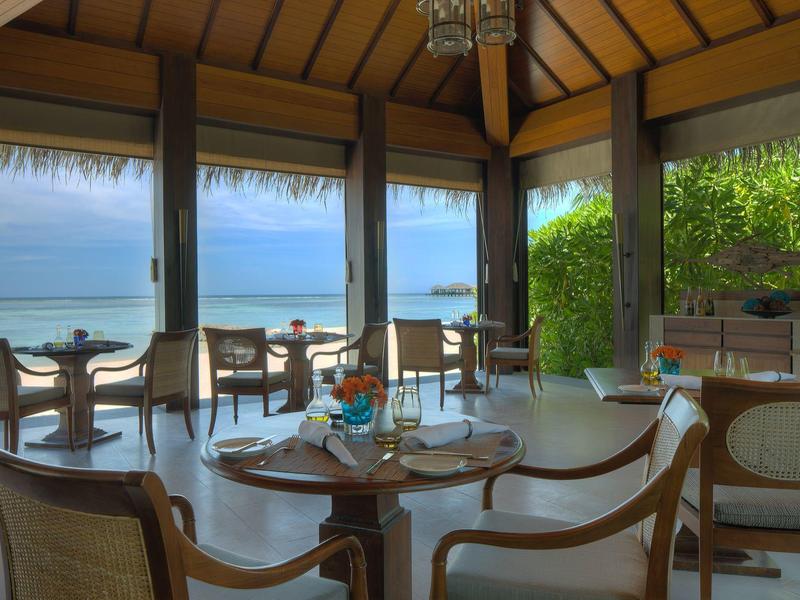 Elegante sala da pranzo con vista mare e grandi finestre in un hotel tropicale.
