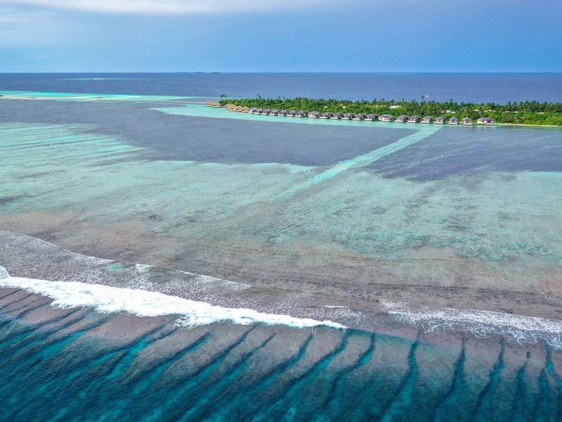 Klares türkisfarbenes Wasser mit einer ruhigen Küste und einer schmalen Landzunge am Horizont.