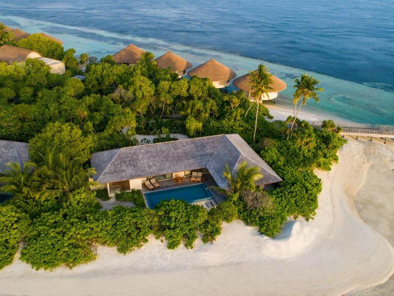 Inselresort mit Strand, üppiger Vegetation und Bungalows am türkisfarbenen Meer.