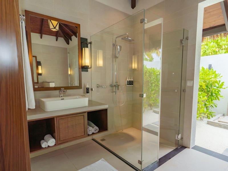 Modernes Badezimmer mit Glasdusche, weißem Waschbecken und Zugang zu Terrasse mit Pflanzen.