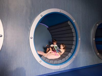 Twee kinderen liggen in een ronde blauwe havenlounge aan het strand.