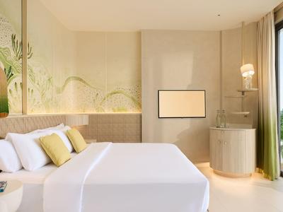 Modernes Hotelzimmer mit großem Bett, sanften Farbtönen und Blick durch Fenster