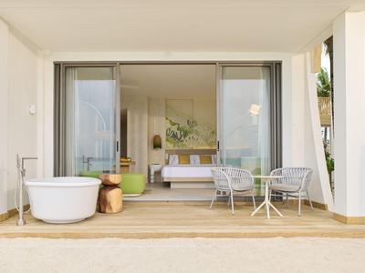 Offene Patio mit Badewanne, Sitzmöbeln und Blick in ein Schlafzimmer mit Doppelbett.