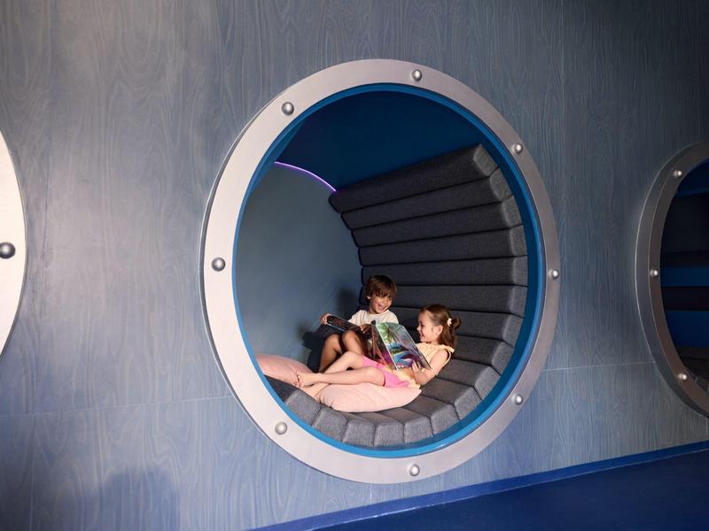 Twee kinderen liggen in een ronde blauwe havenlounge aan het strand.