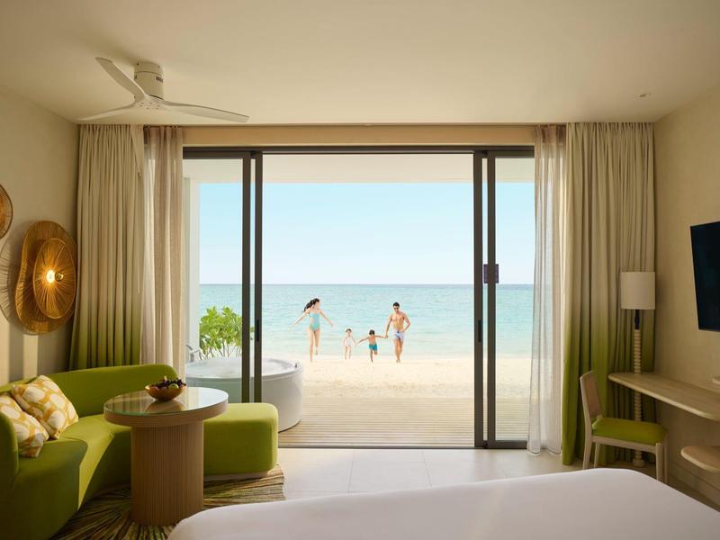 Hotelkamer met uitzicht op strand en zee, open balkon, gezin in het water