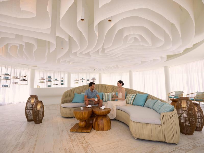 Moderne lichte lounge met ronde bank, houten en rieten meubels in een hotel