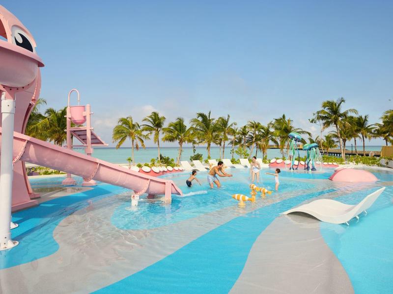 Kinderen in waterpark met glijbanen en palmbomen onder heldere hemel