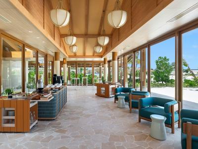 Amplio vestíbulo de hotel con asientos, grandes ventanales y techo de madera.