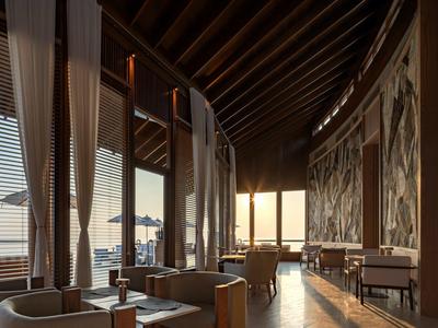 Restaurante moderno con techo de madera, grandes ventanas y vista al mar al atardecer.