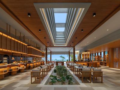 Restaurante de hotel moderno con paneles de madera, gran tragaluz y vista al mar.