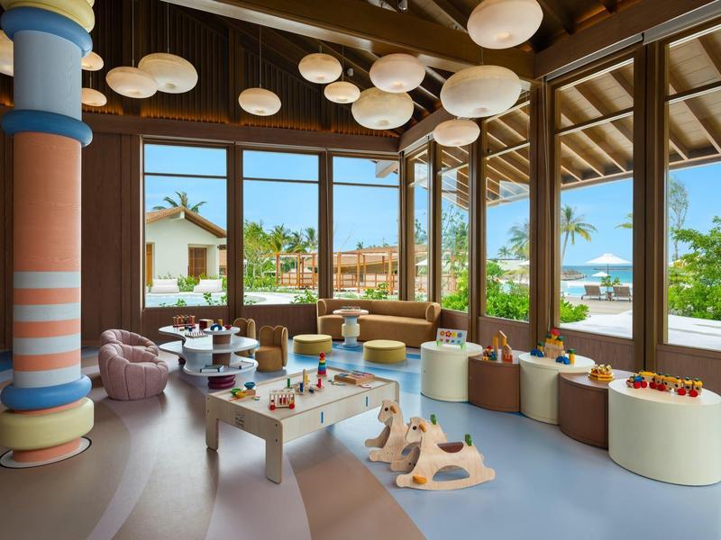 Moderno salón luminoso con grandes ventanas y columnas coloridas.