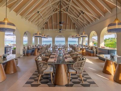 Spacious, bright hotel restaurant with wooden ceilings and sea views.