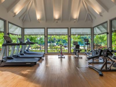 Bright gym with wooden floor and large windows overlooking green gardens.