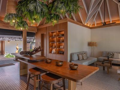 Interior of a modern hotel with wooden table, chairs, and green plants hanging from the ceiling.